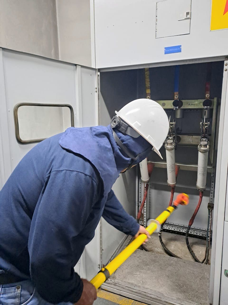 Técnico con pértiga de maniobra en celda de media tensión